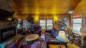 A cozy cabin interior with a fireplace, leather furniture, and wooden walls. - Harvest Moon Cottages - Peacepipe   00088 (Rockbridge)
