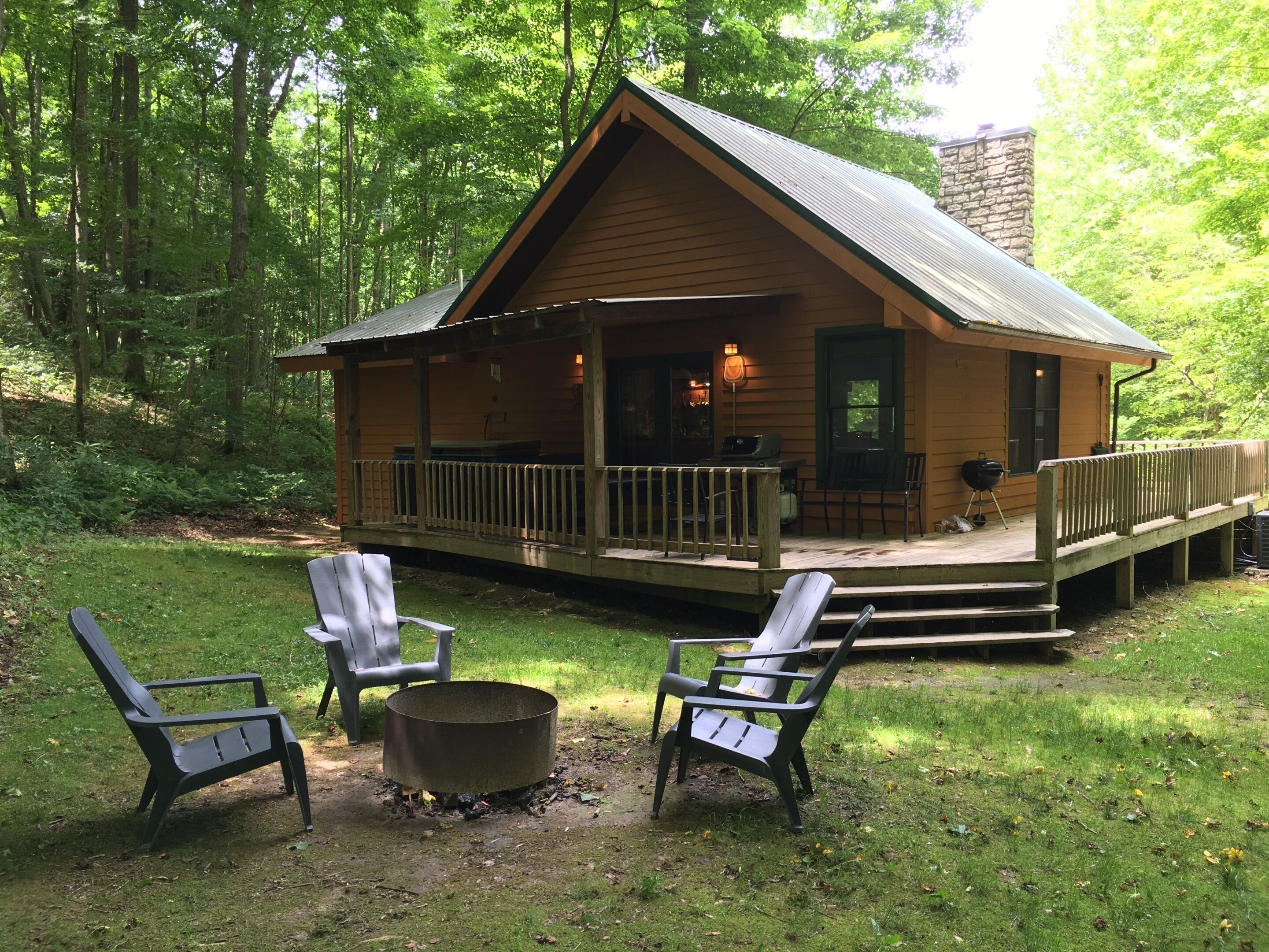 A cabin with a porch, outdoor seating, and a fire pit.
