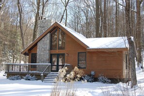 Eine Holzhütte mit Steinkamin, Holzfassade und einer Veranda mit Treppe zum Eingang.