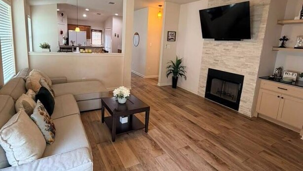 Una sala de estar con un sofá, una mesa de centro, una chimenea y un televisor montado en la pared.