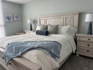 A bedroom with a large bed, two bedside tables, a nightstand, and a lamp.