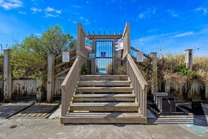 A wooden staircase leading to a gated entrance with warning signs. - Ocean View 2BR Condo • Pets • Balcony • Sleeps 8 (Panama City Beach)