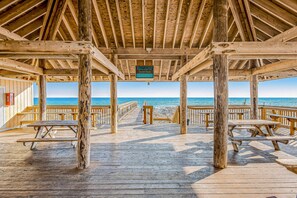 A wooden pier with picnic tables and a sign indicating beach access dedicated to Jerry Voss. - Lovely Beach Front condo with balcony, shared pool & hot tub, & free WiFi (Destin)
