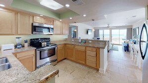 A modern kitchen with granite countertops, stainless steel appliances, and wooden cabinets. - Lovely Beach Front condo with balcony, shared pool & hot tub, & free WiFi (Destin)