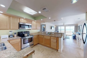 A modern kitchen with granite countertops, stainless steel appliances, and wooden cabinets. - Lovely Beach Front condo with balcony, shared pool & hot tub, & free WiFi (Destin)