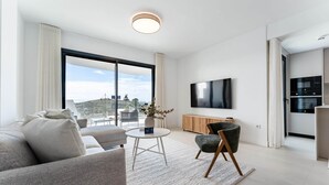 Ett modernt vardagsrum med en soffa, fåtölj, runt soffbord och en platt-TV.