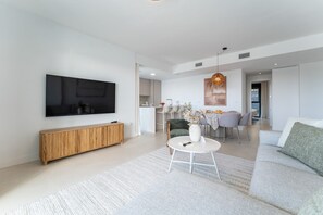 A modern living room with a flat-screen TV, a wooden console, a round coffee table, and a sofa. - Coastal Retreat with shared pool, Fuengirola (Fuengirola)