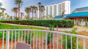 A hotel with a modern design, featuring a large building with multiple balconies, surrounded by palm trees and well-maintained gardens. - Snowbird-friendly condo with pool, hot tub, splash area, tennis, restaurant, gym (Destin)