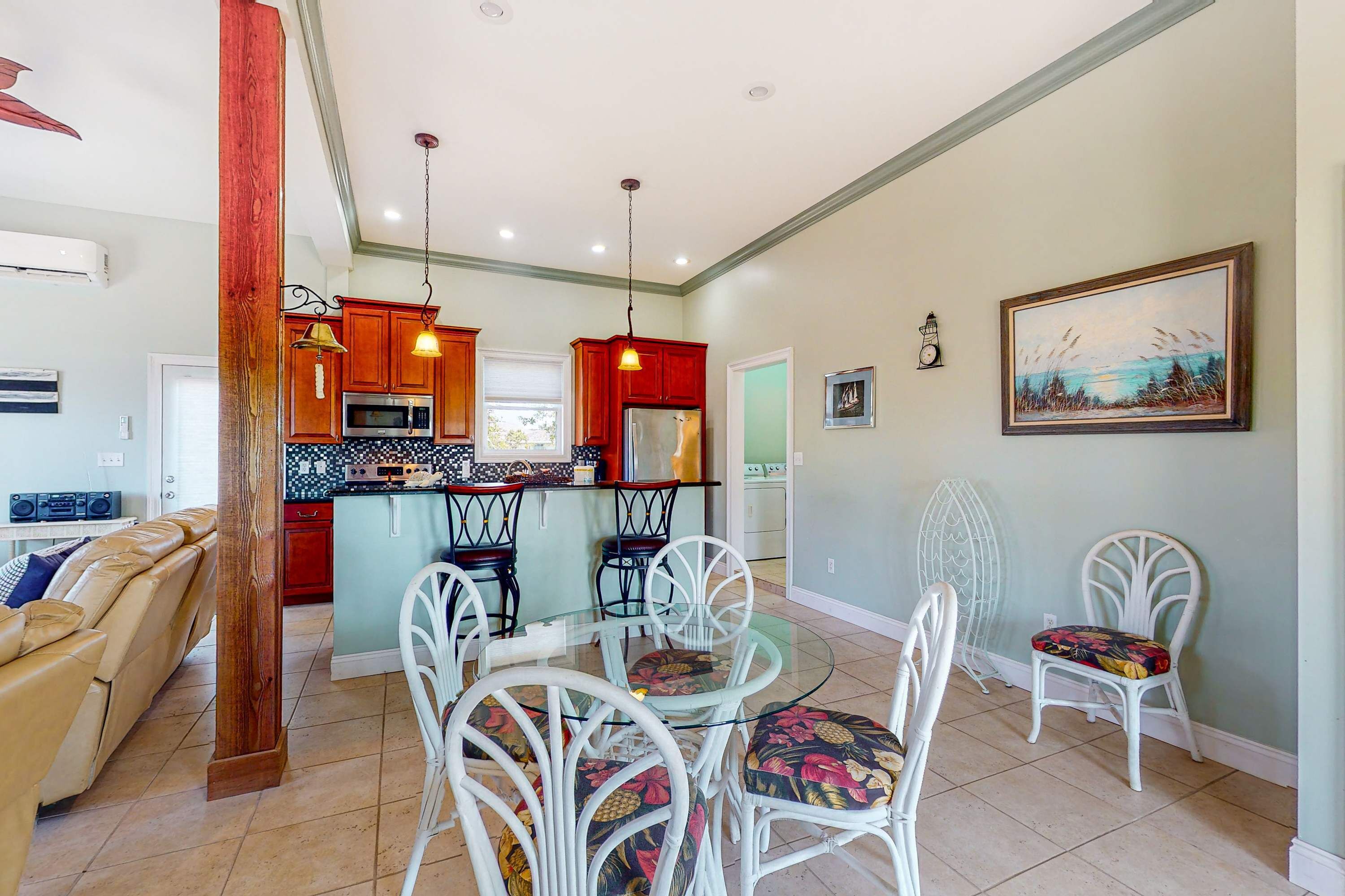 A modern kitchen with wooden cabinets, a central island, and a dining area with white chairs.