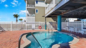 A swimming pool with a white fence, a lifebuoy, and a pool ladder.