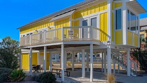 A yellow building with a balcony and a covered patio area. - Beautiful, dog-friendly cottage with deck & patio - stroll to Carrabelle Beach (Carrabelle)