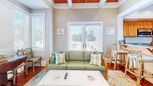 A cozy living room with a sofa, chairs, a coffee table, and a kitchen area with wooden cabinets and a microwave. - Beautiful, dog-friendly cottage with deck & patio - stroll to Carrabelle Beach (Carrabelle)