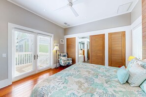 A bedroom with a large bed, wooden wardrobe, and a chair. - Beautiful, dog-friendly cottage with deck & patio - stroll to Carrabelle Beach (Carrabelle)