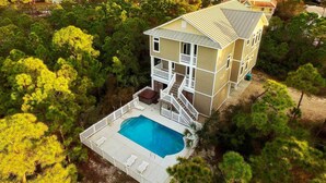 A two-story house with a swimming pool surrounded by a white fence. - Spacious dog-friendly home with pool, hot tub, access to tennis, pickle ball, pools (St. George Island)