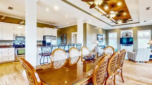A spacious dining area with a glass-top table surrounded by wicker chairs, a ceiling fan, and recessed lighting. - Spacious dog-friendly home with pool, hot tub, access to tennis, pickle ball, pools (St. George Island)