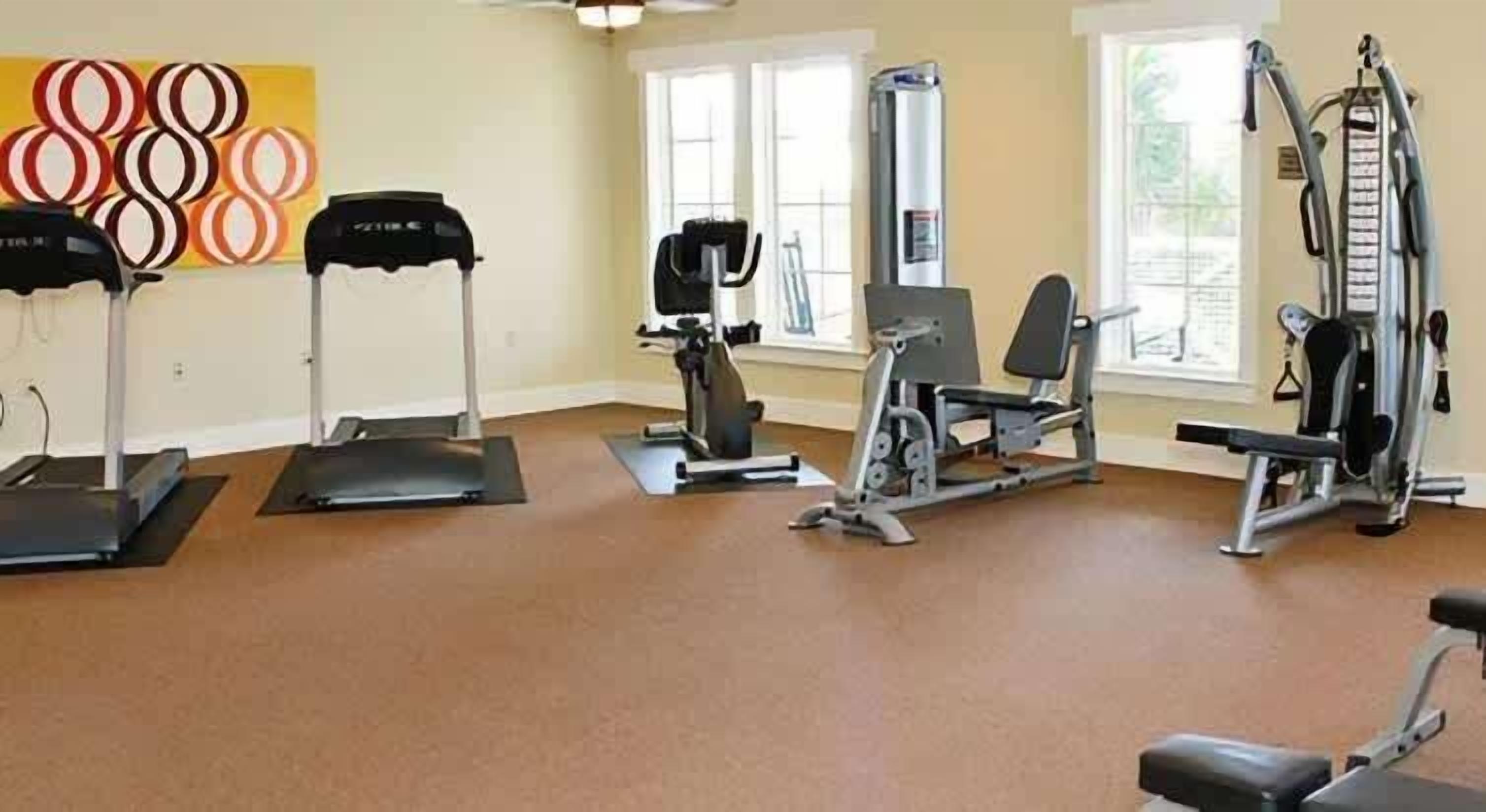 A gym with various exercise equipment including treadmills, a stationary bike, and weight machines.