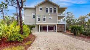 A two-story house with a covered driveway, a balcony on the second floor, and a garage. - Spacious dog-friendly home with pool, hot tub, access to tennis, pickle ball, pools (St. George Island)