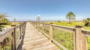 Une promenade en bois qui mène à une plage, avec un ciel dégagé.