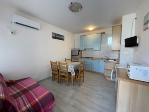 A compact living space with a kitchenette, a dining area, and a sofa. - Inviting Flat for Four Guests in Rosolina Mare (Rosolina)