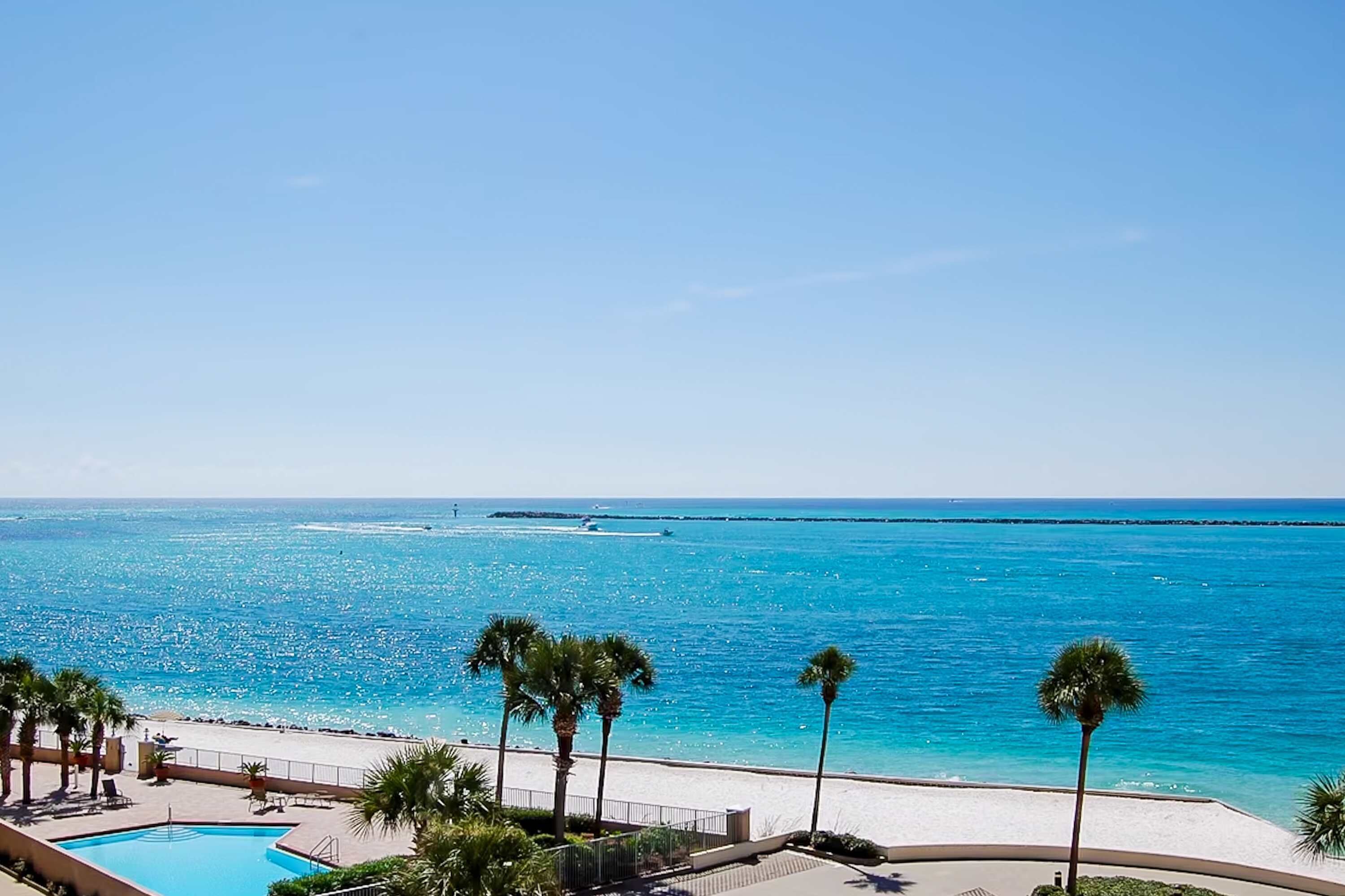 Ein Resort mit Pool, Palmen und Blick auf den Strand.