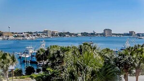 A marina with boats docked, a clear blue sky, and buildings in the background. - East Pass Towers 302 (Destin)