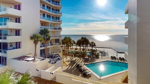 A hotel with a pool, palm trees, and a view of the sea. - East Pass Towers 302 (Destin)