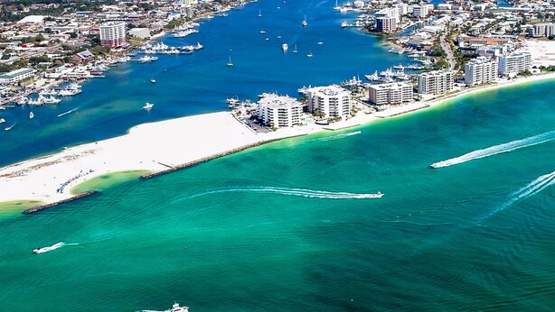 An aerial view of a coastal city with a marina, buildings, and a beach. - East Pass Towers 302 (Destin)