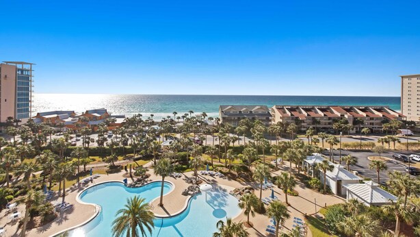 Un resort con una grande piscina, ville fronte spiaggia e vista libera sull'oceano.