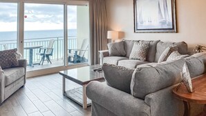 Ein Wohnzimmer mit grauem Sofa, einem Couchtisch und Meerblick durch eine Schiebetür.