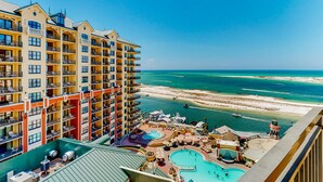 A hotel with multiple balconies overlooking a beach and a swimming pool area. - Gulf-view condo with beach access, pool, hot tub, sauna, & private balcony (Destin)
