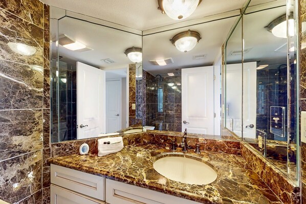 A bathroom with a marble sink, a large mirror, and a modern light fixture. - Ocean-view 2nd-floor condo with outdoor pool, gym, hot tub, balcony, WD, AC (Destin)