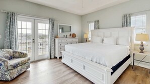 Ein Schlafzimmer mit Bett, Kommode, Stuhl und Deckenventilator.