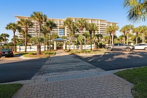 A hotel with a central courtyard, palm trees, and a paved walkway. - Sunny coastal condo with water & pool views - beach access & fitness center (Destin)