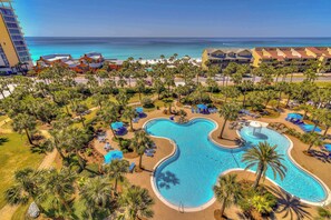 Ein Resort mit großem Pool, Palmen und Blick auf den Ozean.