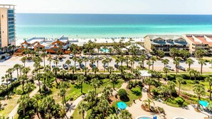 A resort with a beach view, multiple buildings, and a parking area. - Spacious penthouse condo and private balcony, shared pool&fitness, beach access (Destin)