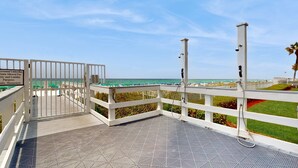 A covered outdoor area with a view of the beach, white railings, and a sign indicating personal umbrellas are allowed. - Gorgeous beach view home with balcony, pool & fitness room (Destin)
