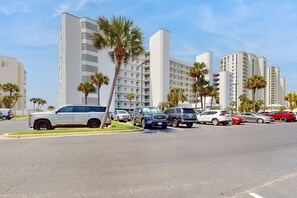 A parking lot with several SUVs and cars, surrounded by tall buildings and palm trees. - Gorgeous beach view home with balcony, pool & fitness room (Destin)