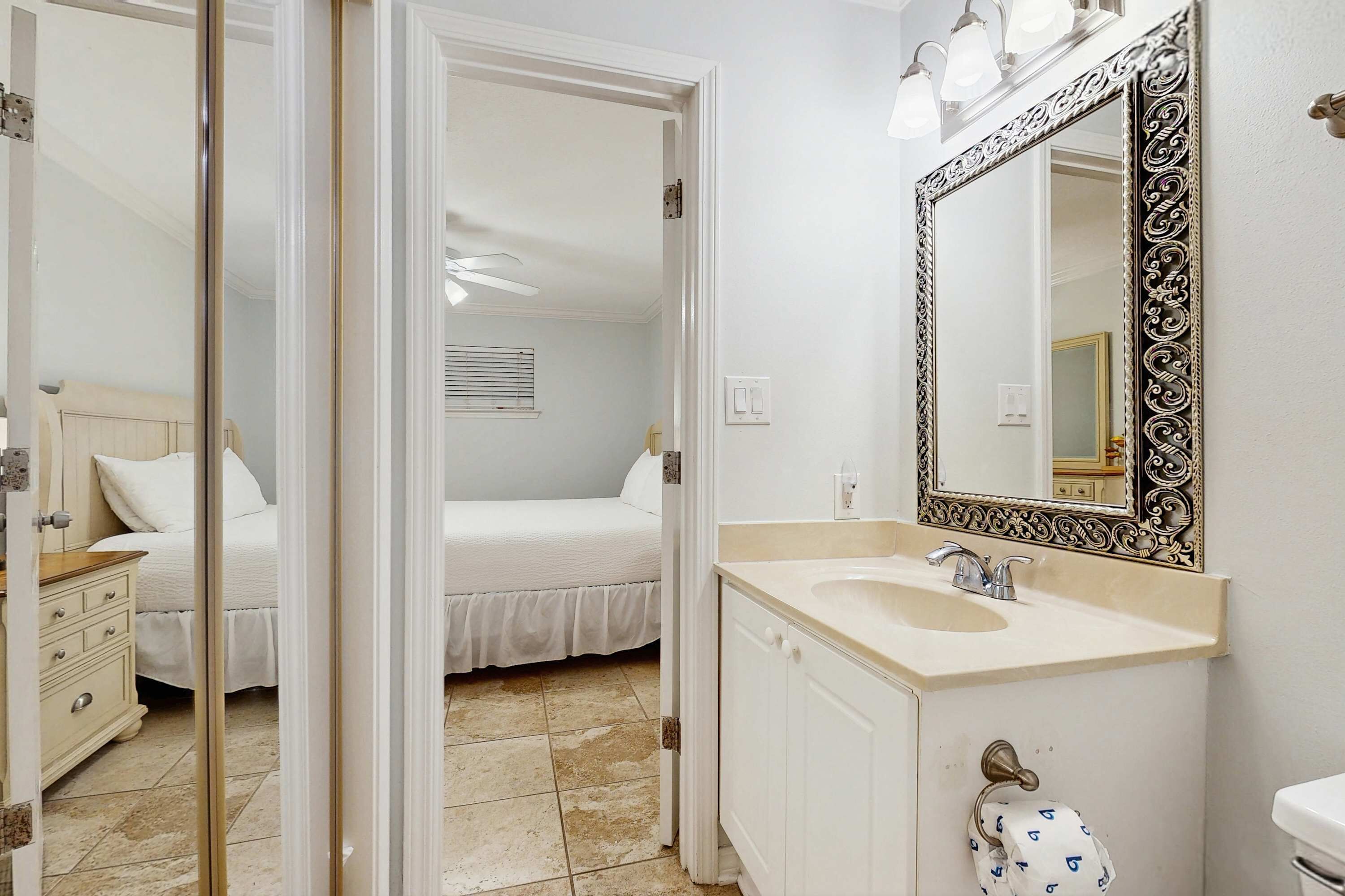 A bathroom with a white sink, a mirror with an ornate frame, and a toilet.