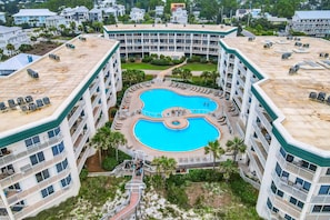 A multi-story hotel with a central swimming pool, balconies, and a rooftop area. - Dunes of Seagrove condo with pool, hot tub, sauna, gym, & tennis,pickleball (Santa Rosa Beach)