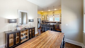 Una cocina moderna con una mesa de comedor de madera, armarios empotrados e iluminación colgante.