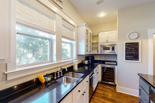 A modern kitchen with a black countertop, white cabinets, and a built-in microwave. - Modern coastal retreat with 2 balconies, grill, central AC, shared Pools, & WiFi (Santa Rosa Beach)