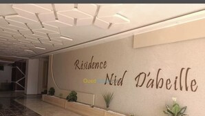A modern interior with a reception area labeled "Résidence Nid D'abeille." - Honeycomb apartment (Béjaïa)