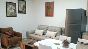 A living room with a sofa, coffee table, and dining table. - Honeycomb apartment (Béjaïa)