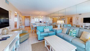 Ein modernes Wohnzimmer mit einer Sofagarnitur, einem Fernseher und einem Essbereich.