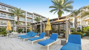 A rooftop pool area with lounge chairs and umbrellas. - Pool-view condo with on-site pool, hot tub, roof deck, gym, & balcony (Inlet Beach)