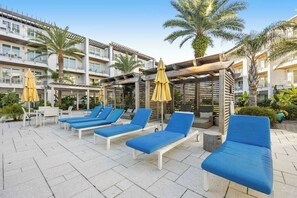 A rooftop pool area with lounge chairs and umbrellas. - Pool-view condo with on-site pool, hot tub, roof deck, gym, & balcony (Inlet Beach)