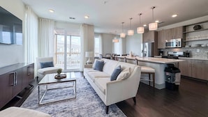 A modern living room with a sofa, coffee table, and a view to the outside. - Pool-view condo with on-site pool, hot tub, roof deck, gym, & balcony (Inlet Beach)