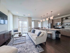 A modern living room with a sofa, coffee table, and a view to the outside. - Pool-view condo with on-site pool, hot tub, roof deck, gym, & balcony (Inlet Beach)