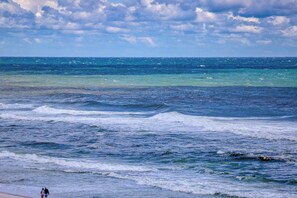 Ein Strand mit brechenden Wellen und wolkenlosem Himmel.