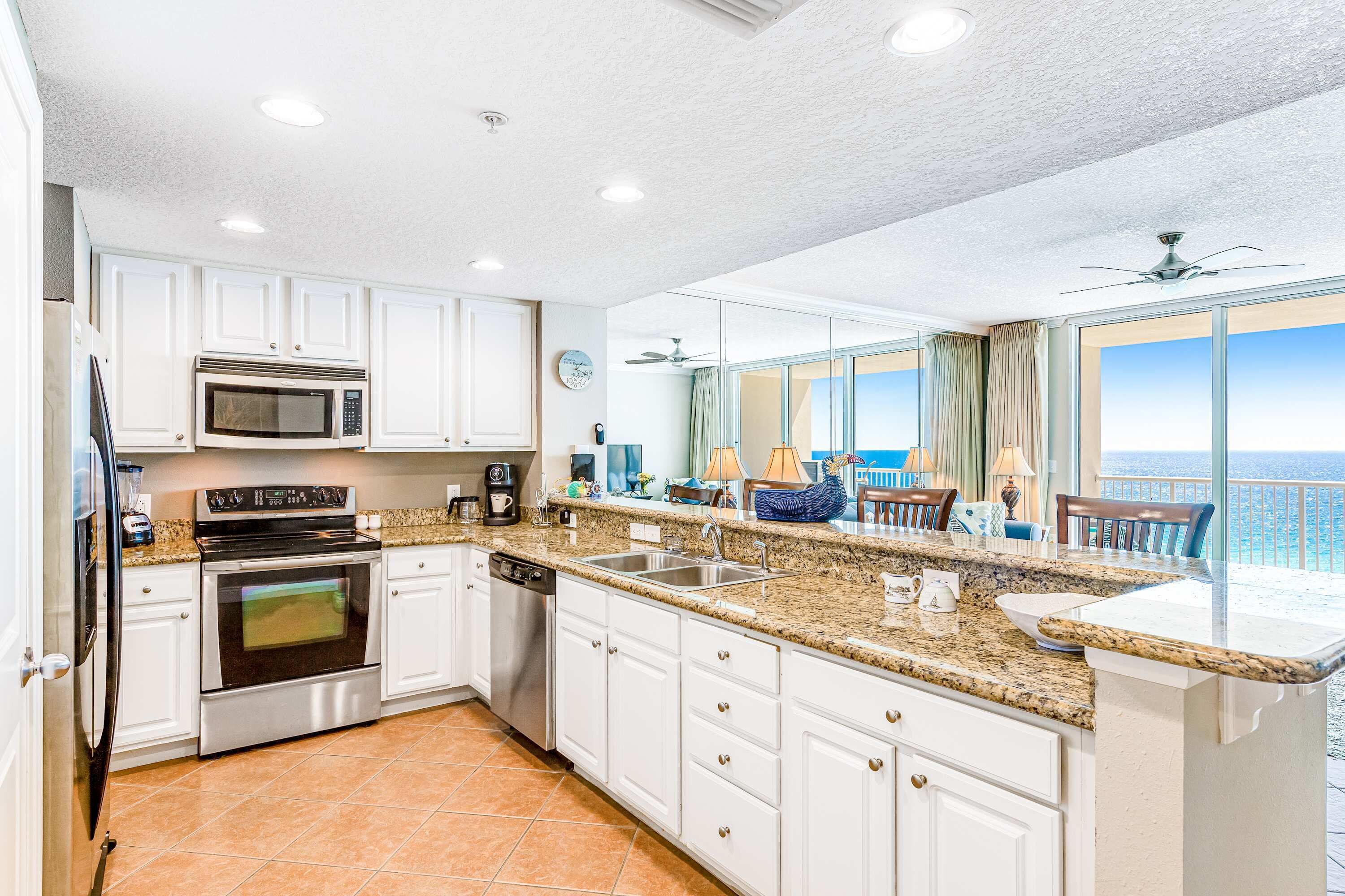 A modern kitchen with white cabinets, stainless steel appliances, and a granite countertop.